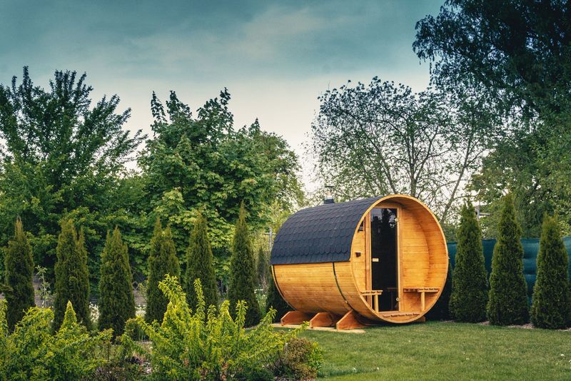 Sauna Beczka WarmEscape w ogrodzie, między tujami