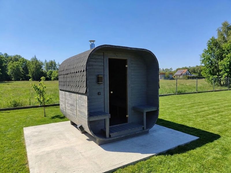 Sauna Quadro z otwartym przedsionkiem na betonowej płycie w ogrodzie